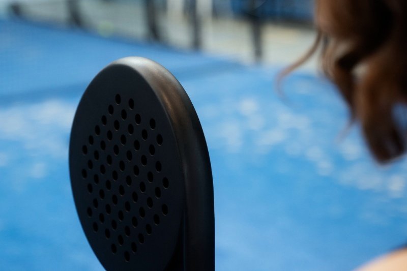 Black Padel Racket Focus Close-up of black padel racket with blurred court background