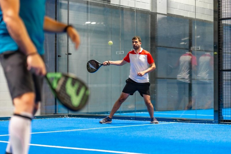 Padel Forehand Action padel player preparing forehand shot during indoor match on blue court