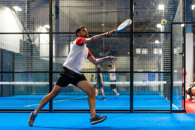 Padel Reach Shot padel player stretching to hit ball during competitive indoor match