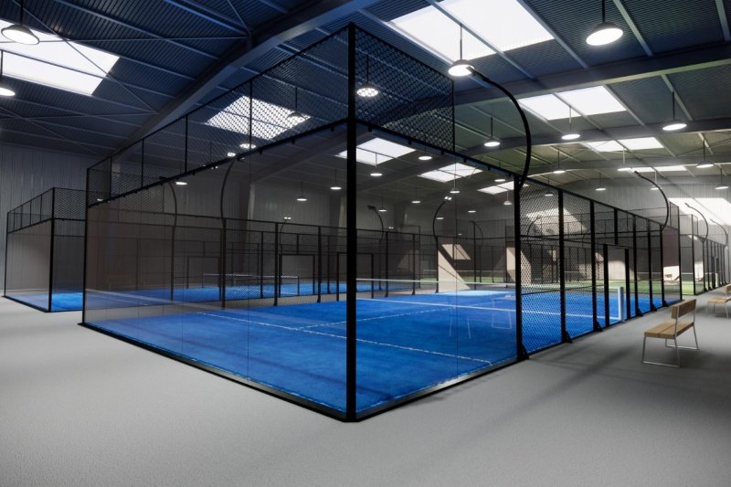 indoor-padel-court Indoor padel courts with blue floors and modern lighting and seating