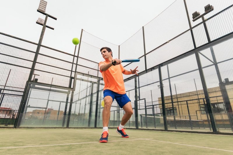padel-action-shot Man playing padel with a yellow ball on a court