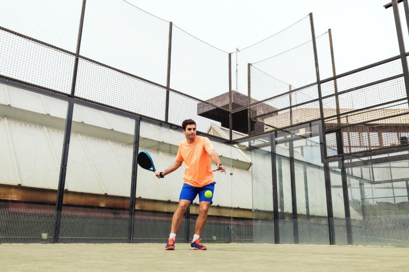 padel-player-action Man playing padel with a blue racket and yellow ball on the court