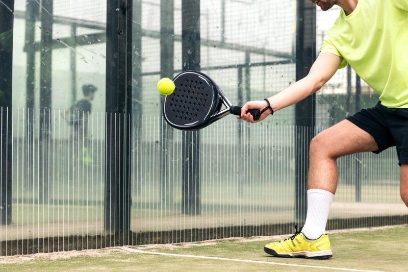padel-action-shot Man hitting padel ball with a black paddle on the court