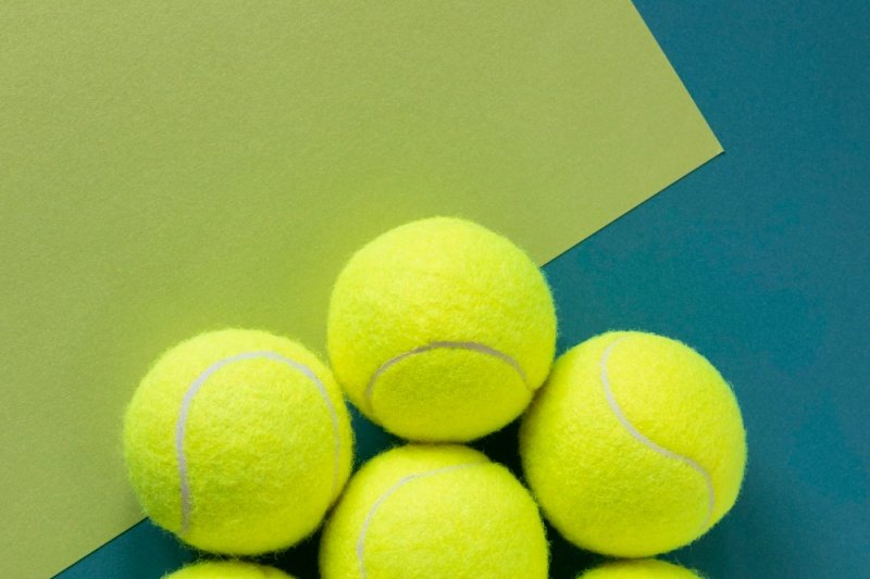 padel-tennis-balls-arranged Group of yellow padel tennis balls on a teal and green background