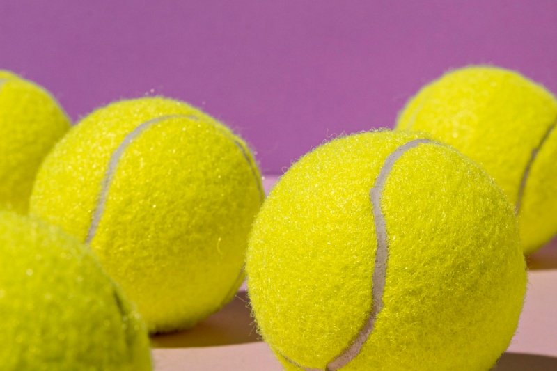 padel-tennis-balls-closeup Close-up of several bright yellow padel tennis balls against a purple background