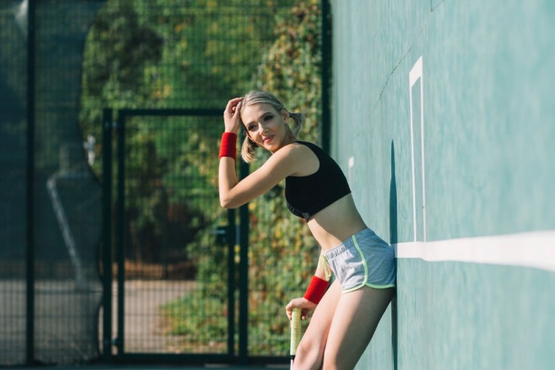 Padel Court Break Female athlete in sportswear leans against padel court wall