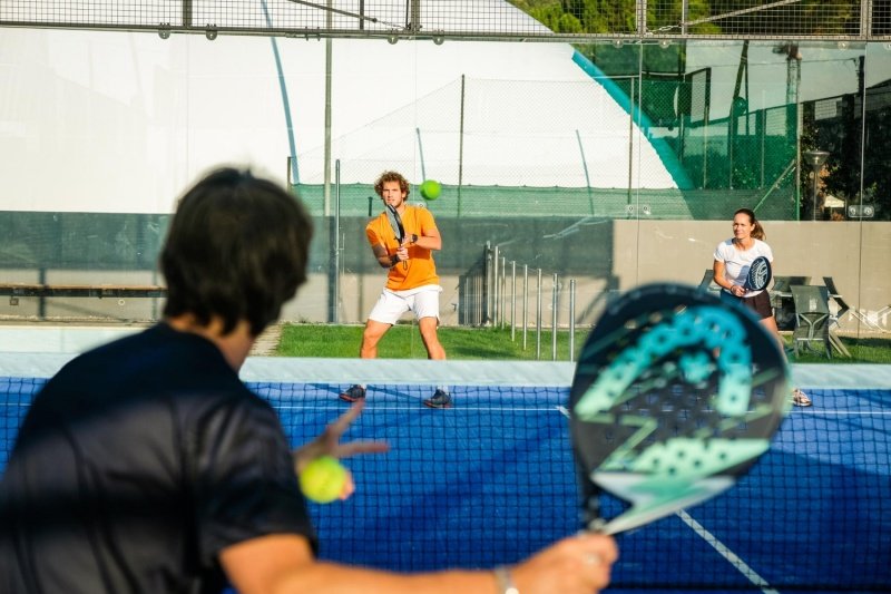 Padel Doubles Match Mixed doubles padel match with player ready to return serve