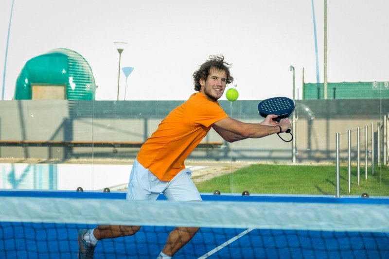 Padel Net Backhand Smiling padel player prepares backhand volley near net