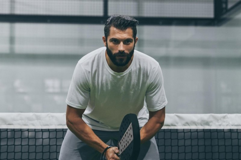 Padel Net Focus Focused male padel player in ready position at net
