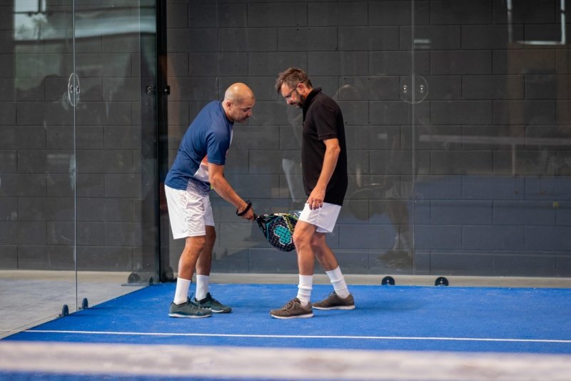 Padel Racket Discussion Two padel players examine racket together during indoor session