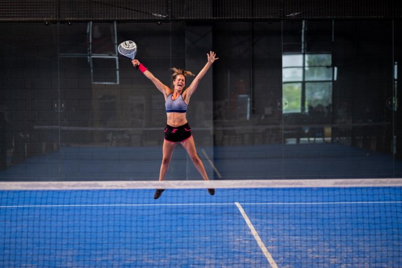 Padel Smash Action Female padel player jumps for smash shot on indoor court