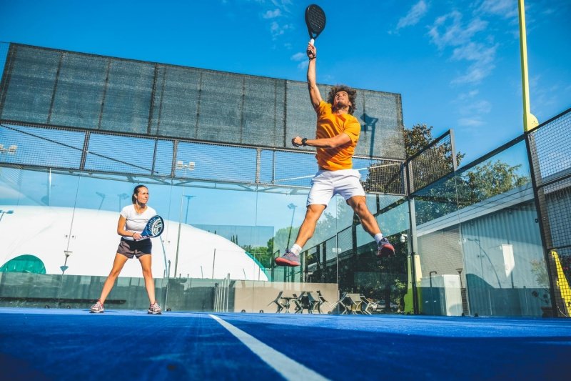 Padel Smash Jump Padel player jumps for powerful overhead shot as teammate watches