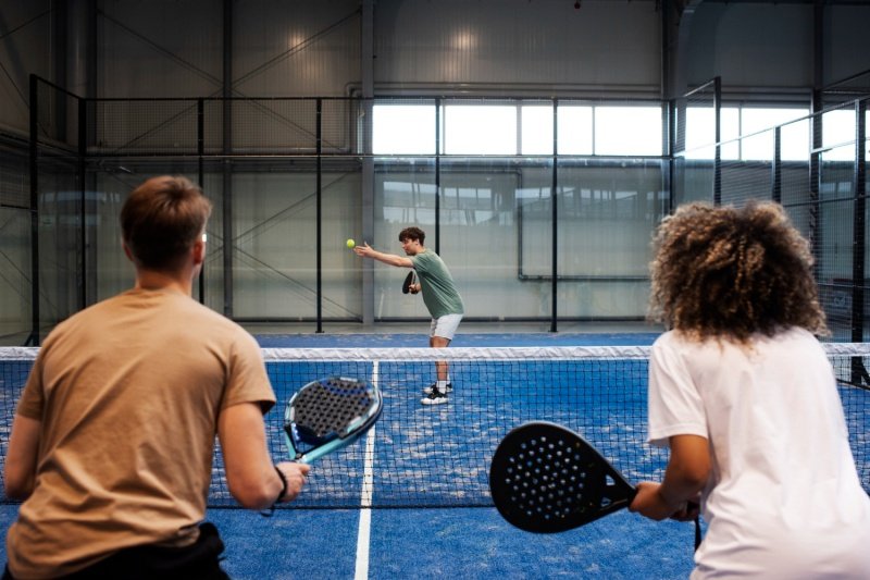 padel match play two players preparing to return serve in indoor padel match