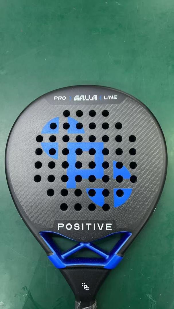 carbon padel racket gray carbon fiber padel racket with blue geometric logo and drilled holes on green surface