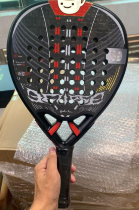 carbon padel racket black carbon padel racket with red accents and multiple drill holes held above packaging
